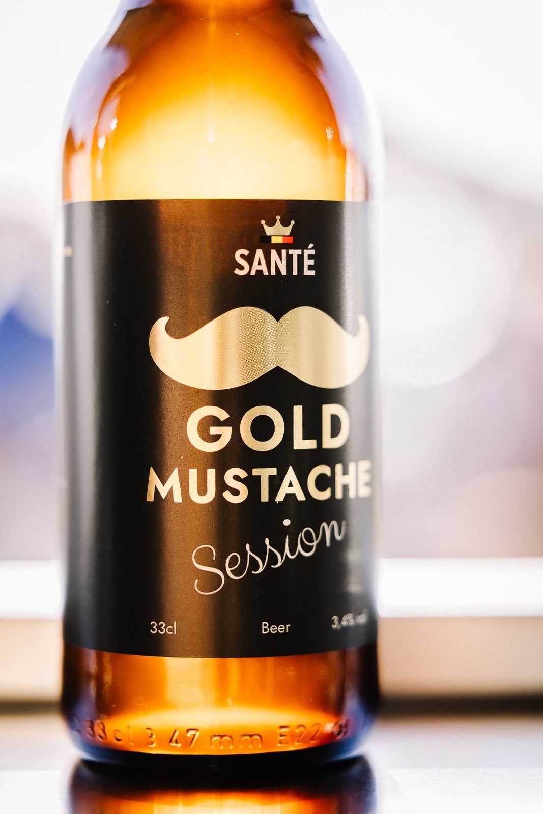 Close-up van het etiket van Gold Mustache Session: de gouden snor, de kroon en 3,4% vol